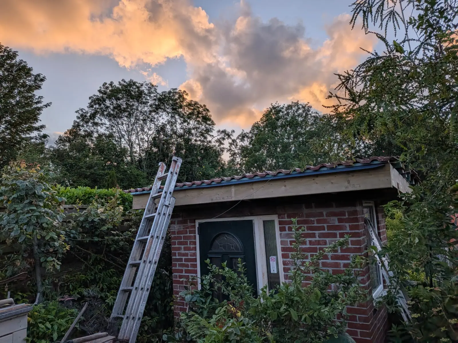 New timber roof structure and pantiles fitted to a brick outbuilding at dusk