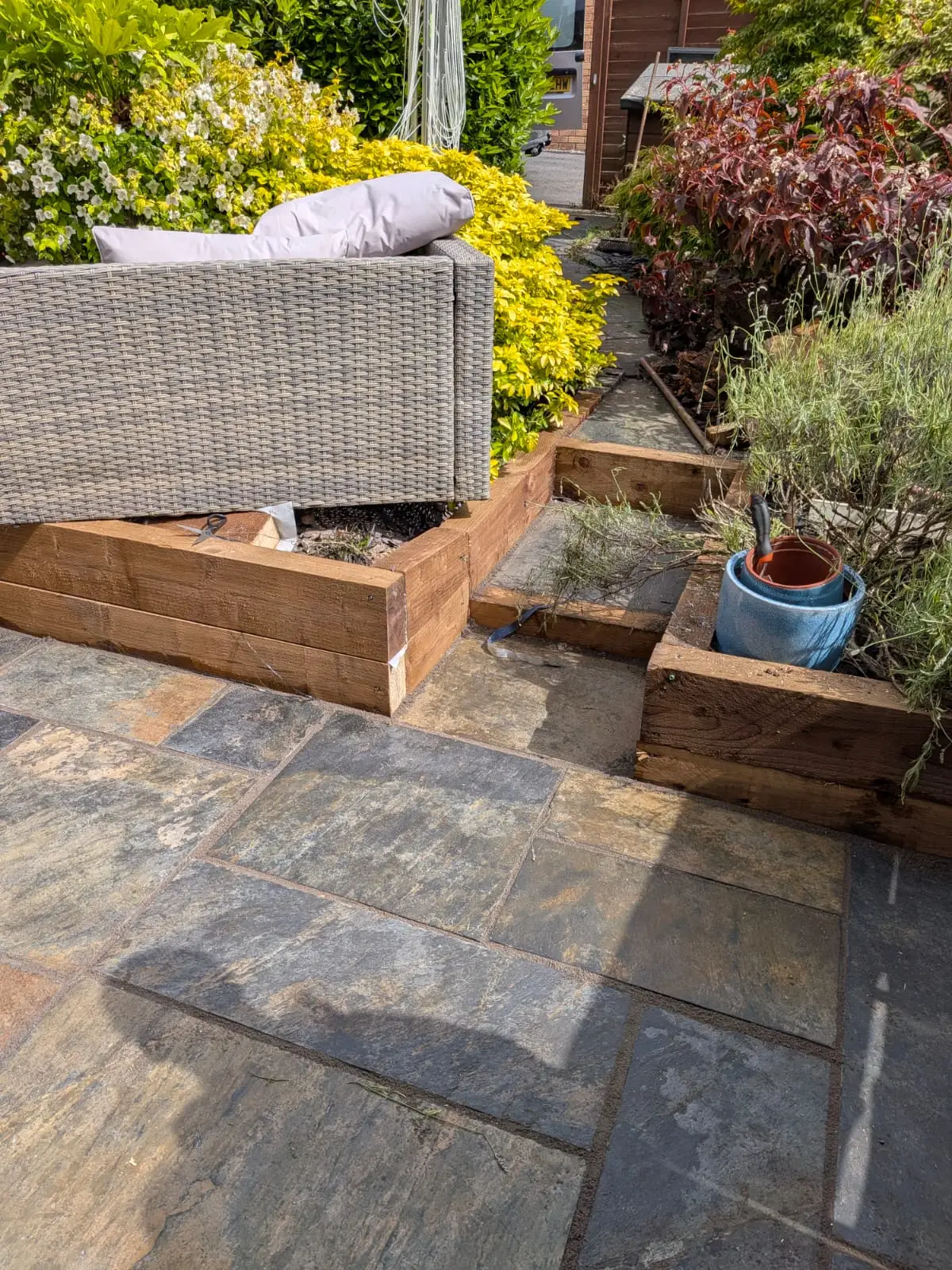 Multi tone slate patio with new sleeper raised beds framing a seating area