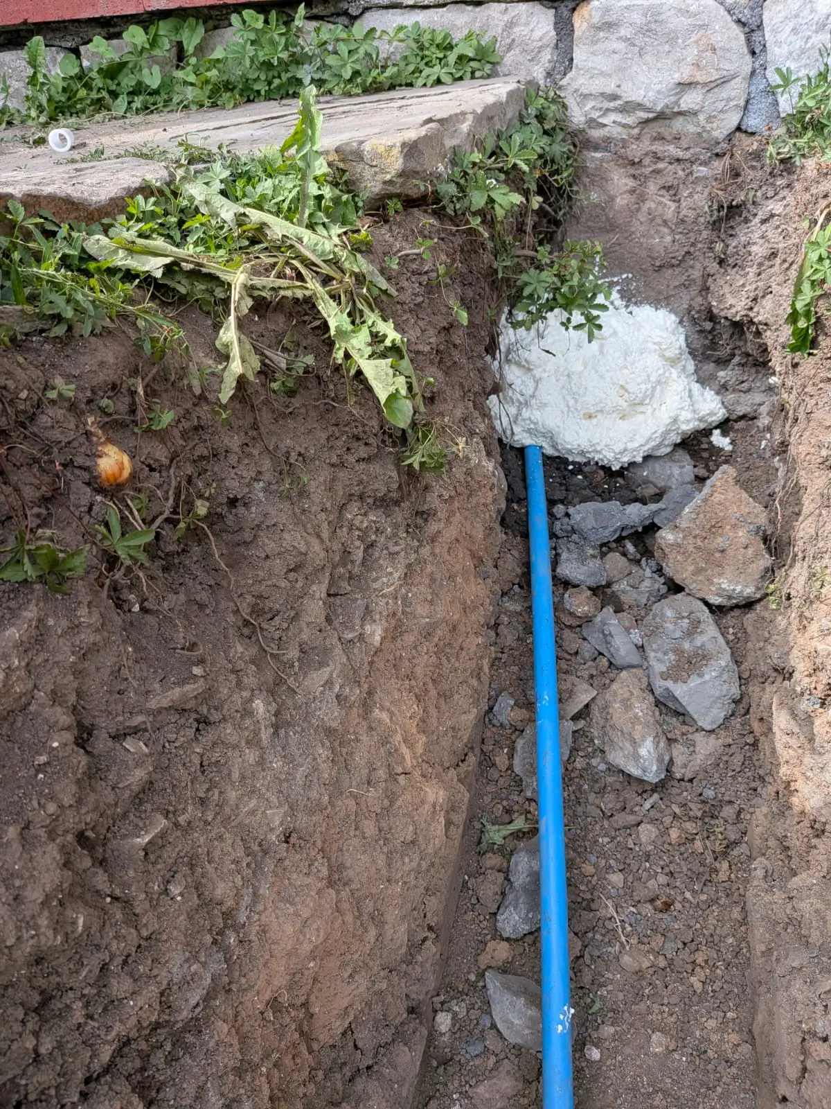 Water main running through a deep trench and foamed where it passes through the wall