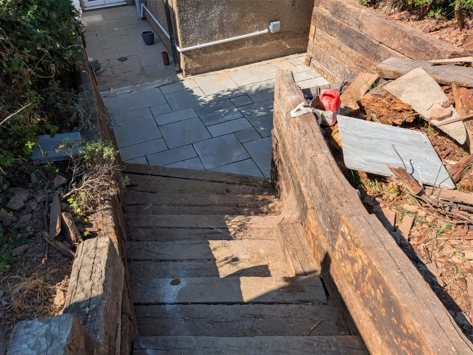 Sleeper steps rising from a slate patio, retaining the bank either side